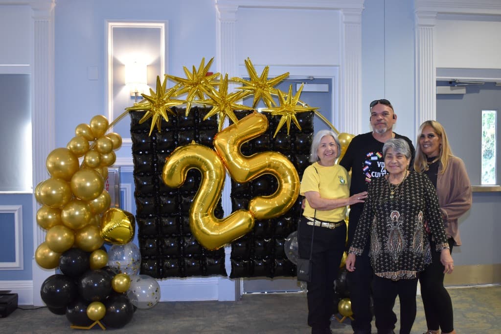 Community members and supporters posing at the 25th anniversary display