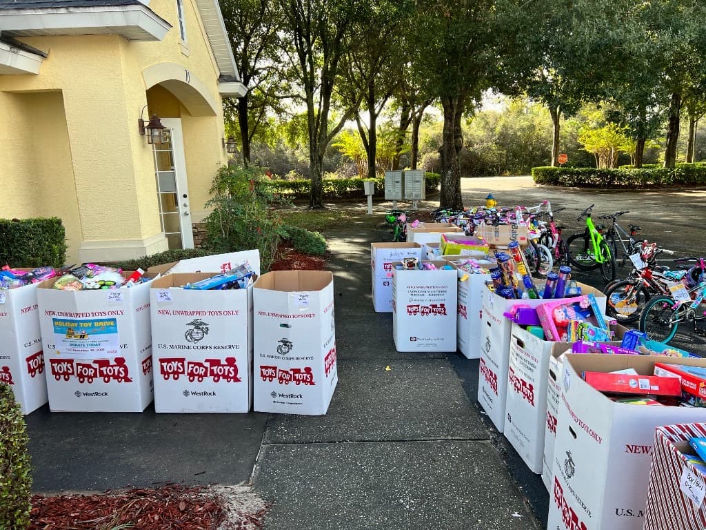 Volunteers organizing donated toys beside a line of children's bicycles in the parking lot
