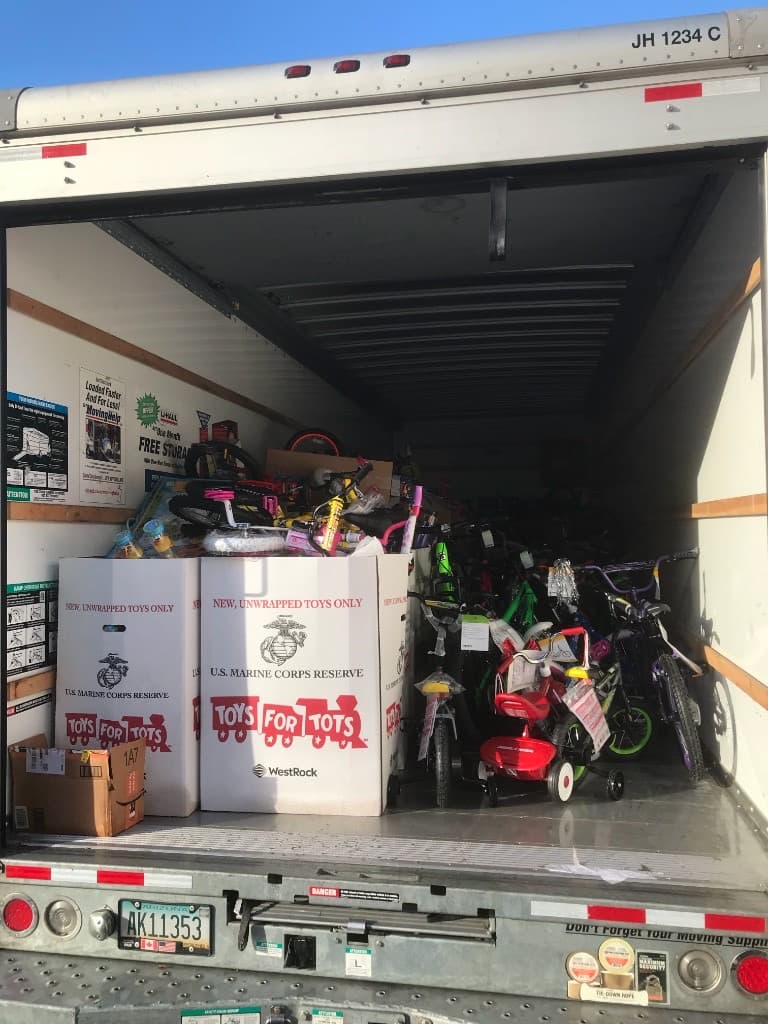 Indoor room filled with sorted Toys for Tots donations organized by age group