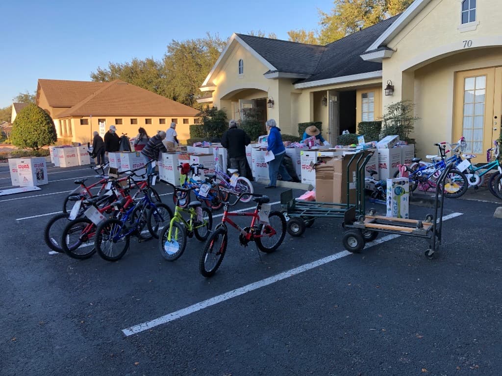 Volunteers in festive hats taking a selfie beside a Toys for Tots donation box