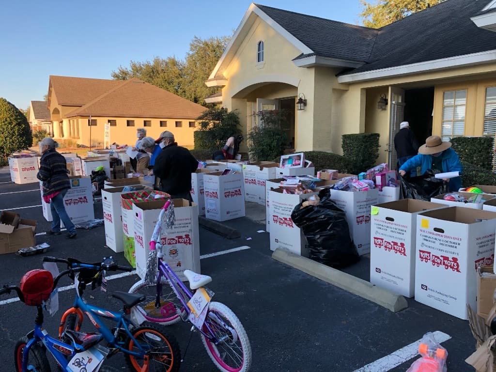 Volunteers sorting dozens of Toys for Tots boxes in the sunny parking lot