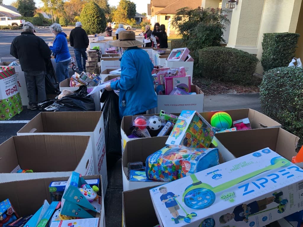 Community volunteers carrying holiday donations toward the Toys for Tots collection area