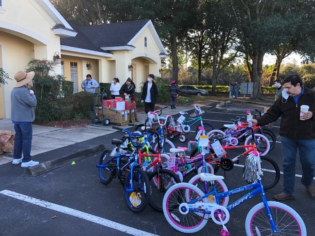 Rows of white Toys for Tots bins filled with new toys and children's bicycles outdoors
