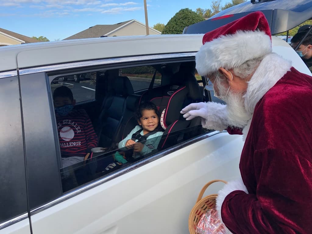 Santa Claus and a volunteer delivering a child's bicycle to a family at the drive-through event