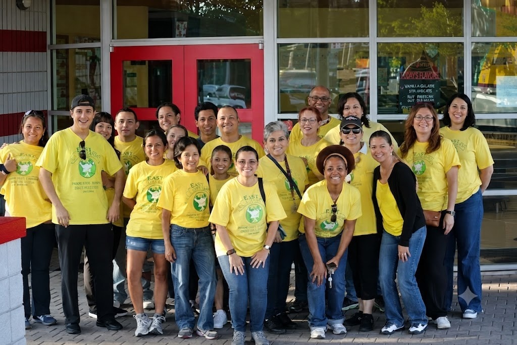 HHI volunteers in yellow Hispanic Health Initiatives shirts posing together outside the DeBary office